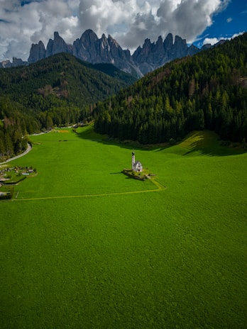 A small community church in a rural village surrounded by lush greenery and mountains.