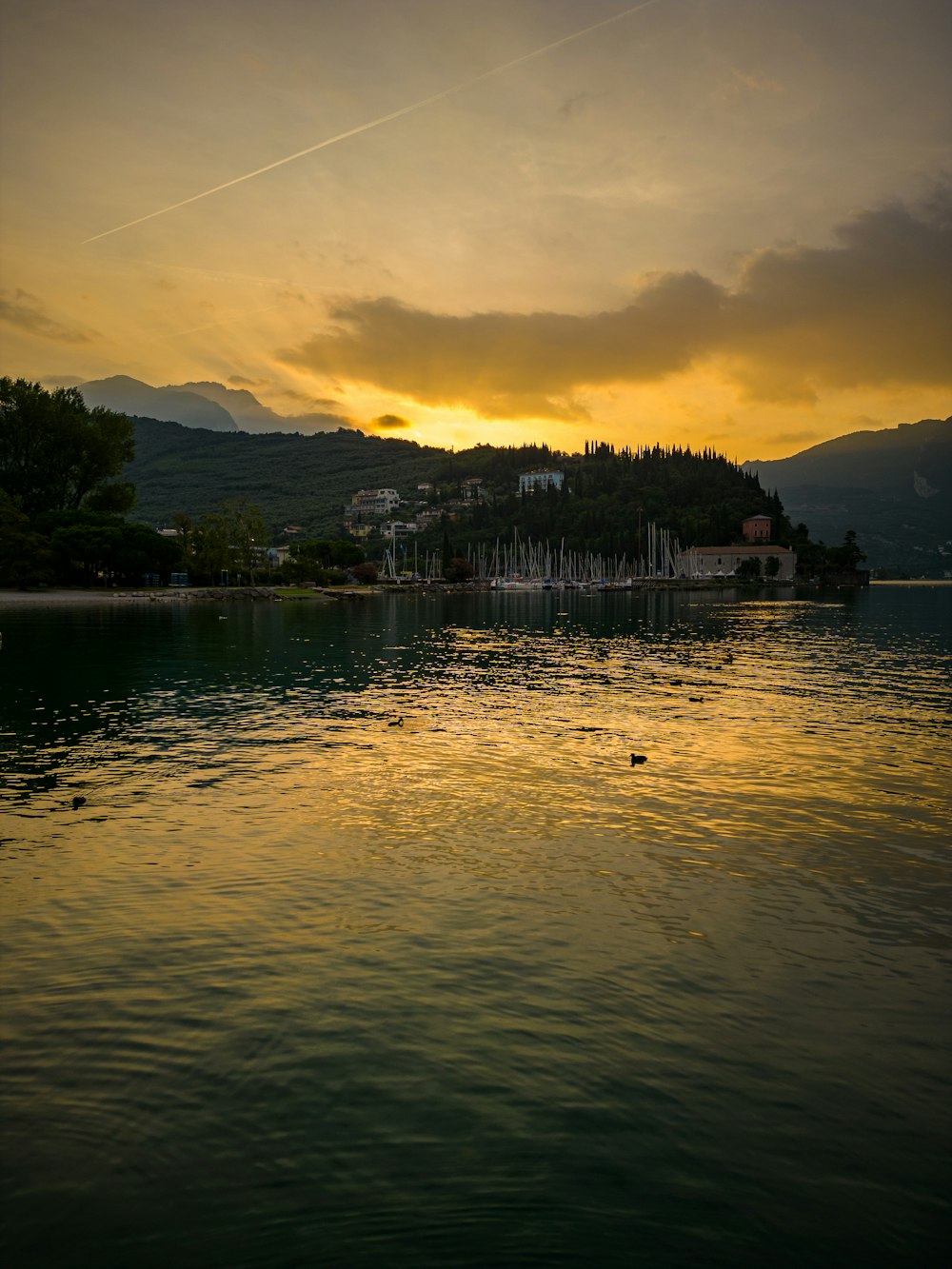 the sun is setting over a lake with a small island in the distance