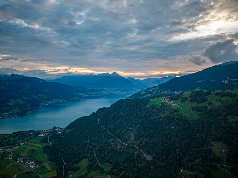 a scenic view of a lake and mountains under a cloudy sky