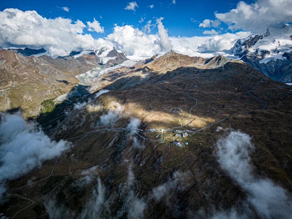 an aerial view of a mountain range with clouds in the sky