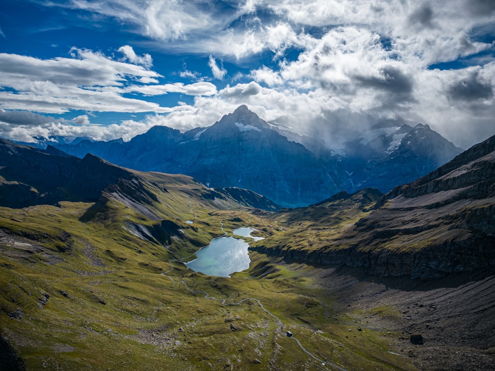 a lake surrounded by mountains under a cloudy sky