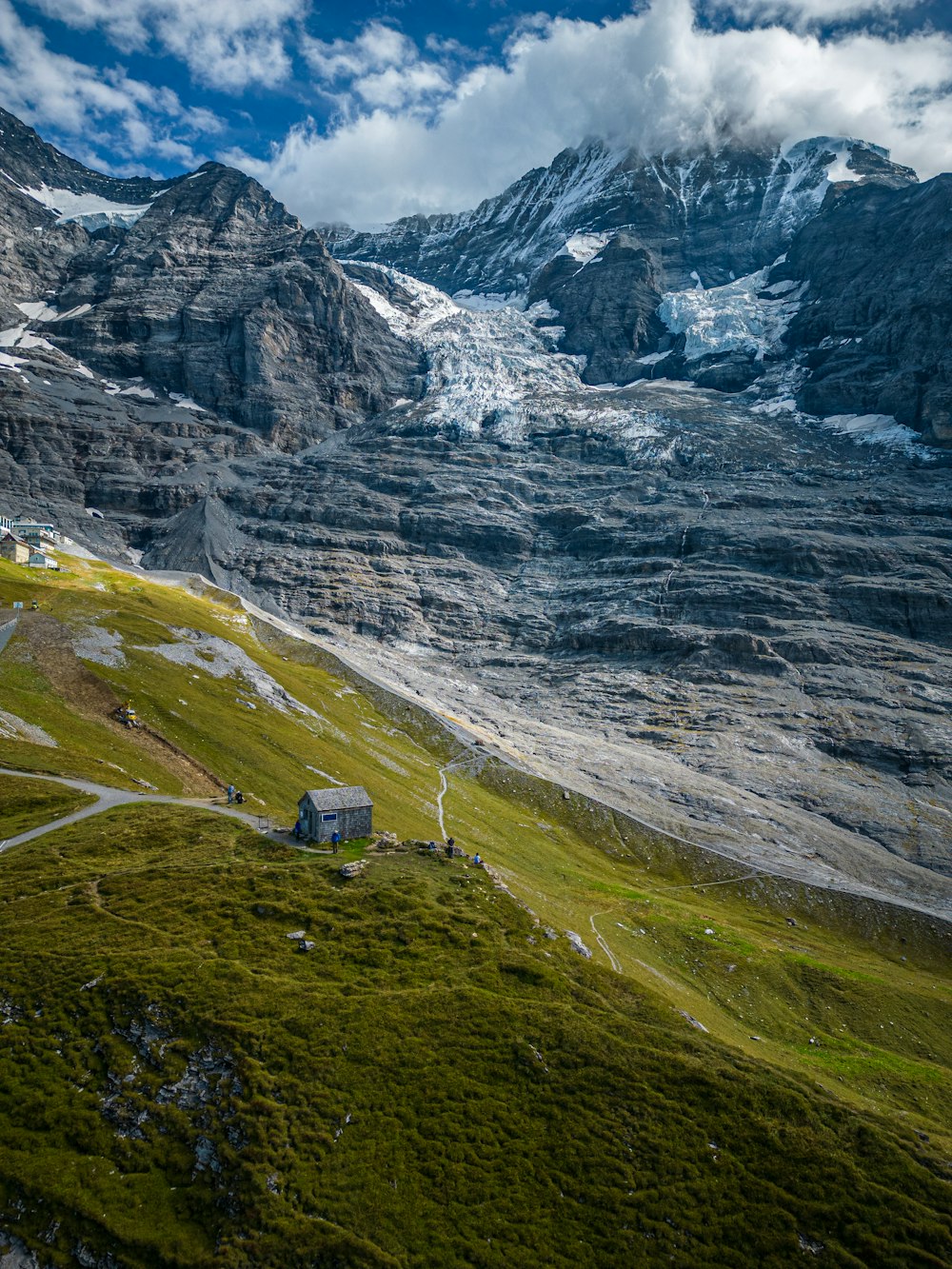 a house on a grassy hill with a mountain in the background