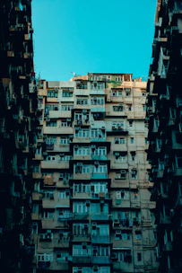 Apartment building facade with multiple windows fitted with discreet air vents under cloudy sky.