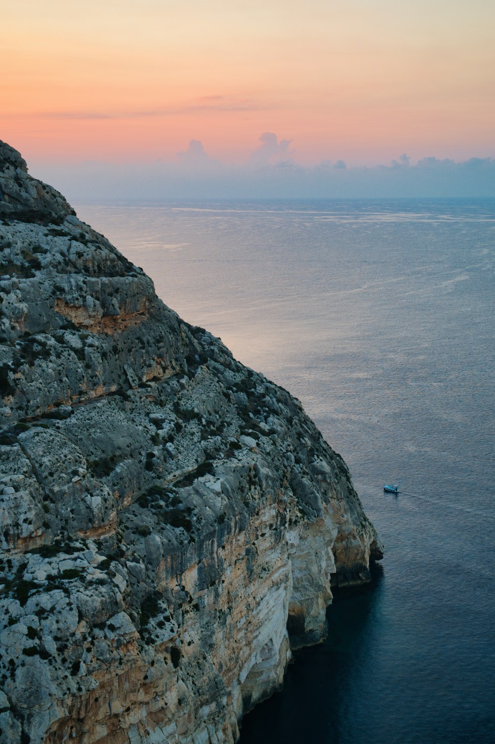 a boat is on the water near a rocky cliff