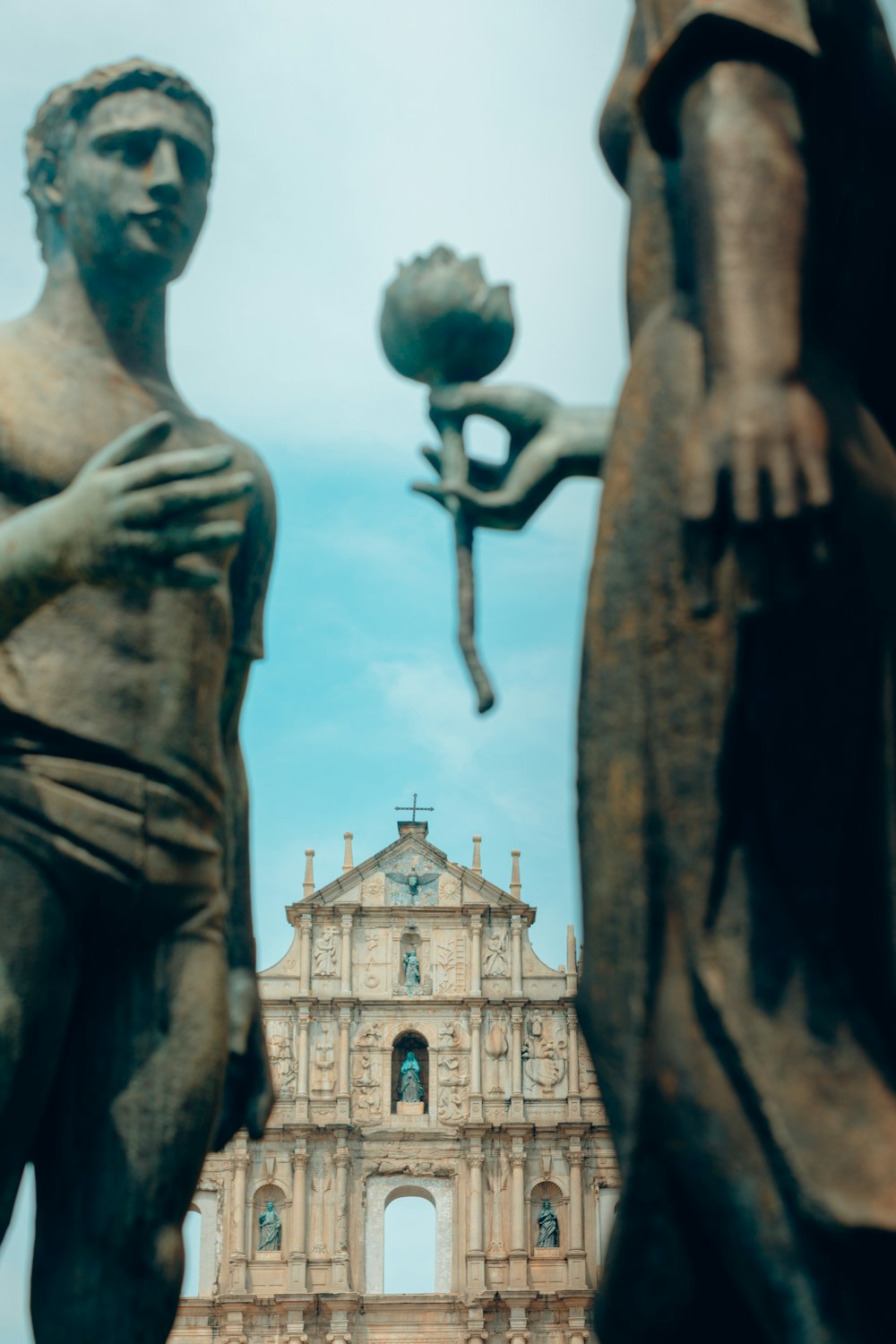 a statue of a man holding a flower next to a statue of a woman