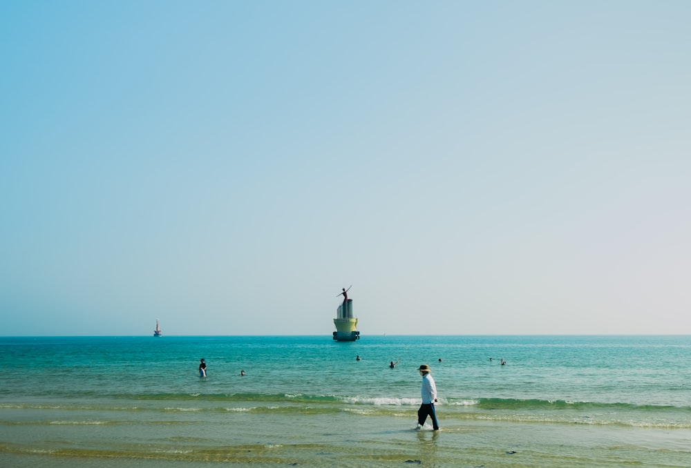 a group of people standing on top of a beach next to the ocean