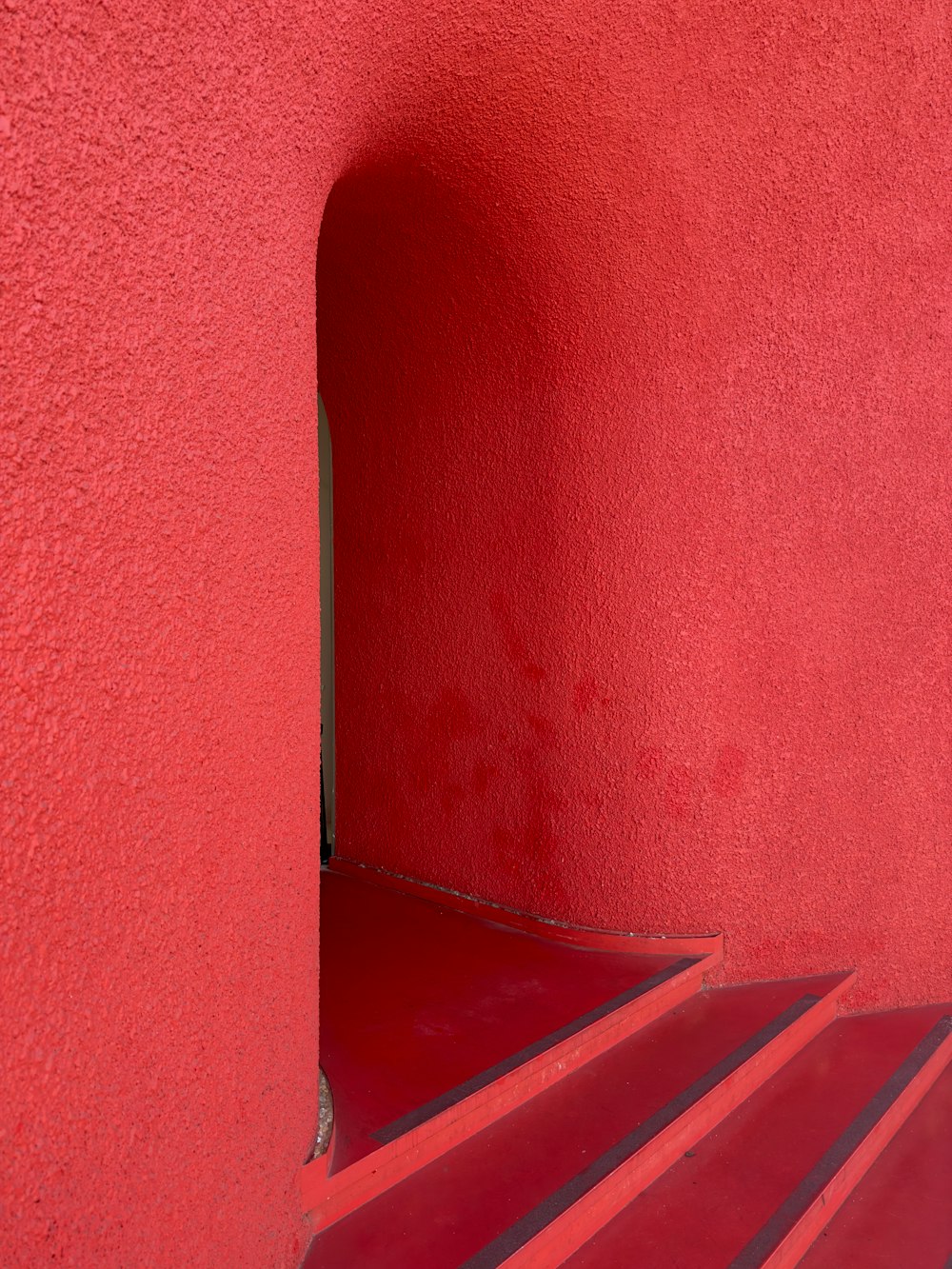 a red wall with a set of stairs leading up to it