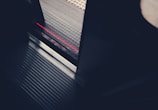 A partial view of a train or subway door with a visible threshold. The floor of the transport vehicle is metallic with grooved lines, and there is a contrasting textured platform outside. A red line runs along the edge of the platform as a warning marker.