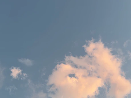 A soft blue sky with delicate white clouds drifting gently, evoking a sense of calm and escape.