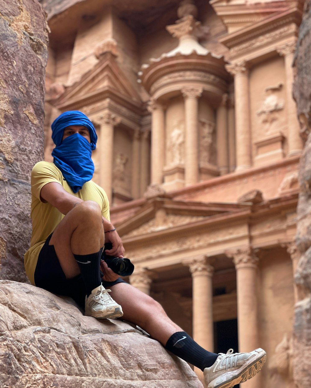 a man sitting on a rock in front of a building