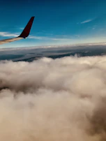Aerial shot of a jet soaring above the clouds during a clear blue sky day.