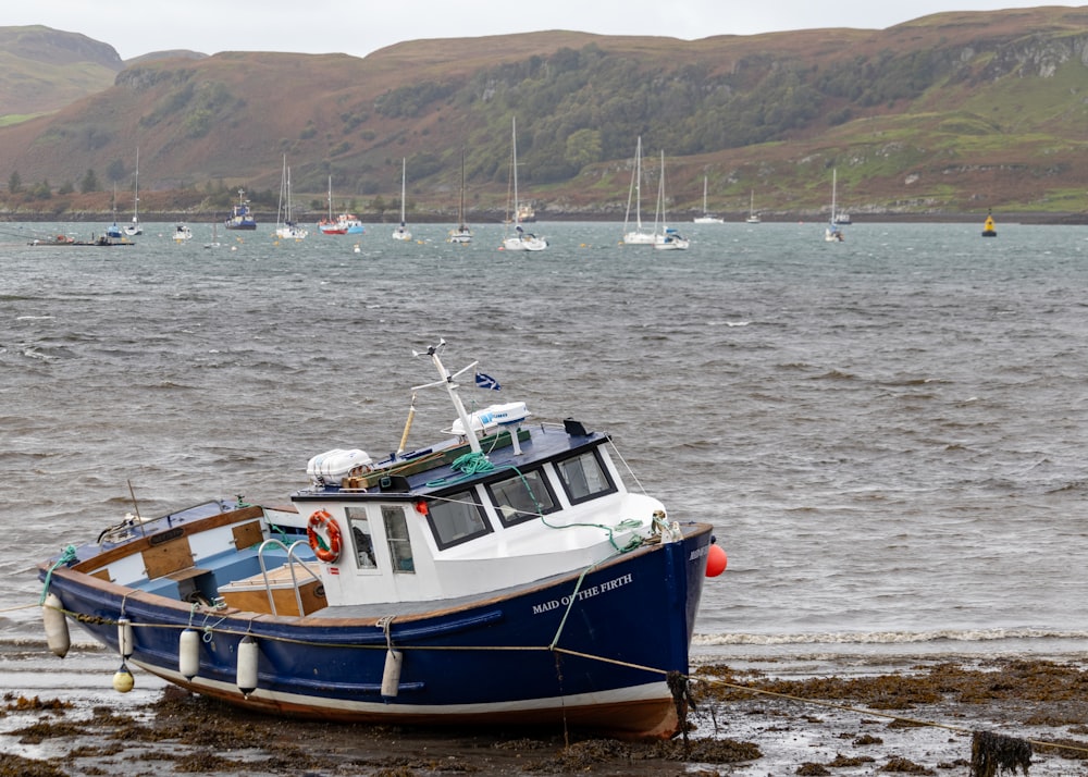 a blue and white boat sitting on top of a beach