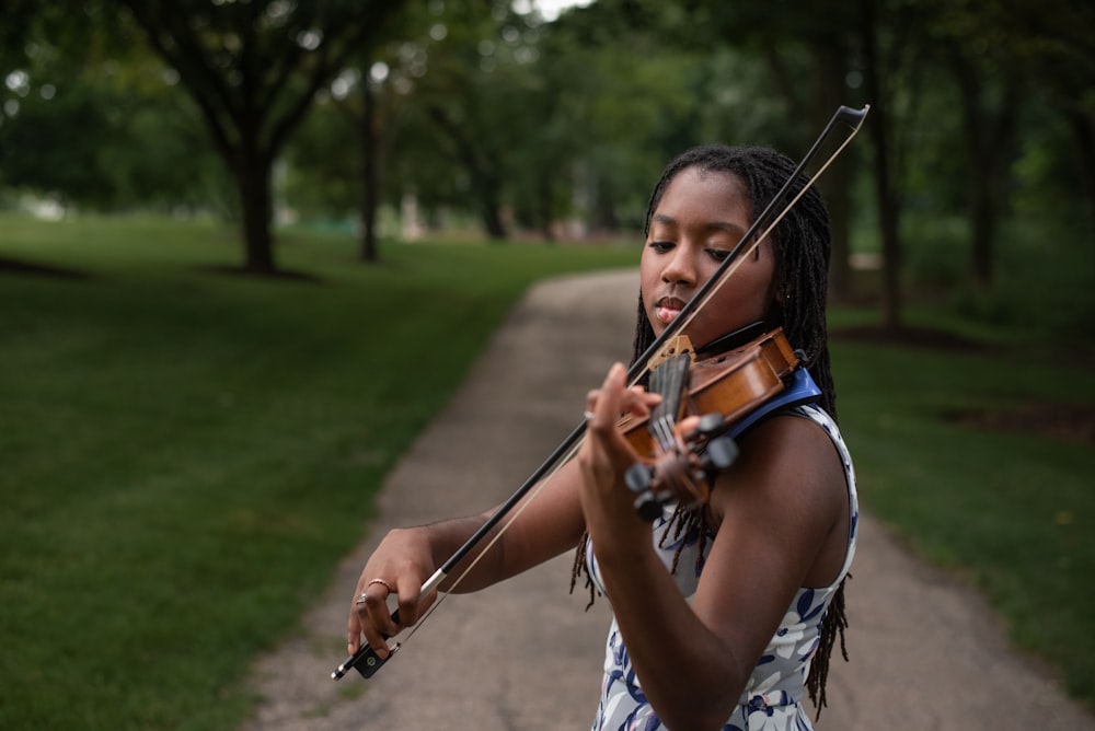 a young girl playing a violin in a park