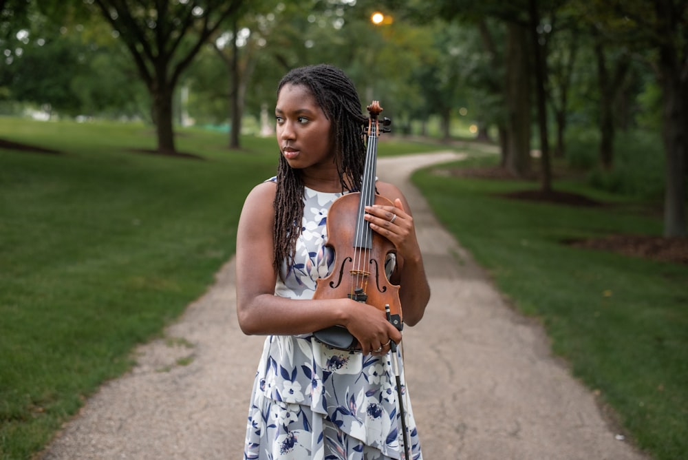 a woman holding a violin in a park