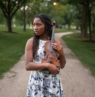 a woman holding a violin in a park