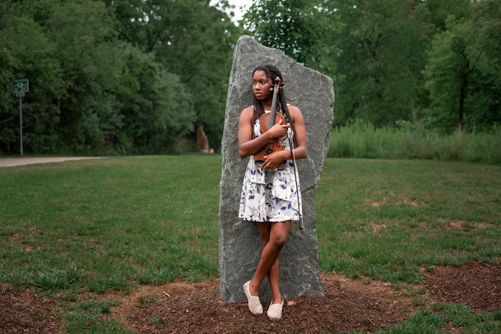 a woman standing in front of a large rock