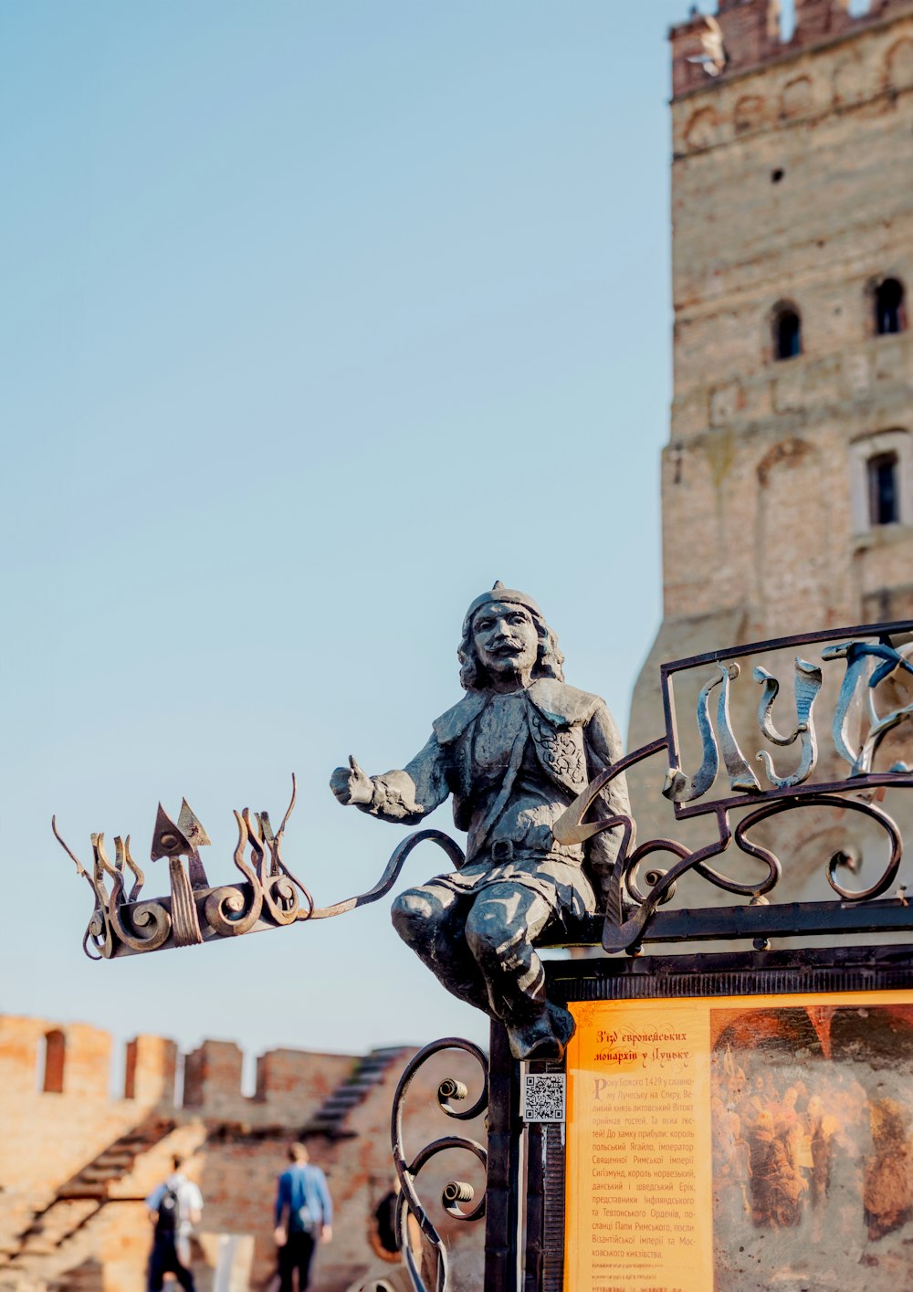 a statue of a man holding a cat on top of a gate