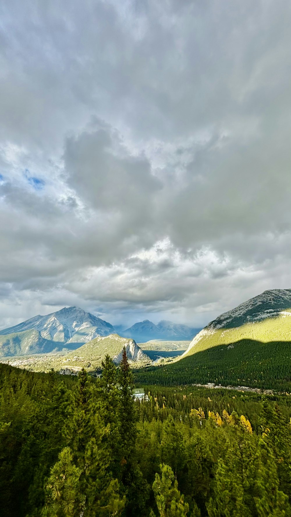 a scenic view of mountains and trees under a cloudy sky