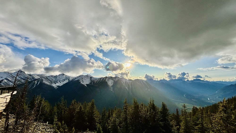 the sun is shining through the clouds over the mountains