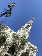 Quiet street scene with church steeple rising against a soft blue sky.