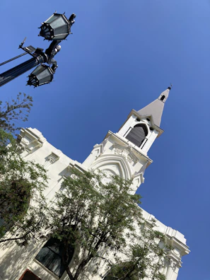 Quiet street scene with church steeple rising against a soft blue sky.
