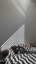 A comfortable bed with white linens and soft natural light in a minimalist hotel room.