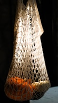 An elegant display of organic cotton mesh bags filled with gold-tier mangoes, illuminated by soft, luxurious lighting.