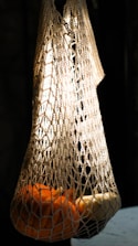 Luxurious organic cotton mesh bags draped over deep charcoal crates under soft lighting.