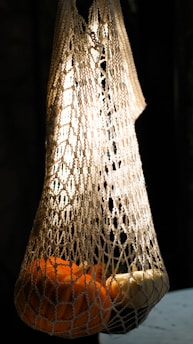 An elegant display of organic cotton mesh bags filled with gold-tier mangoes, illuminated by soft, luxurious lighting.