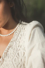 Close-up of a finely embroidered neckline on a creamy silk dress under soft natural light.
