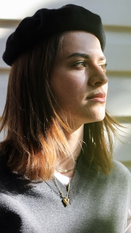 Close-up of a soft, retro-style beret resting on a vintage wooden table with a warm sunlight glow.
