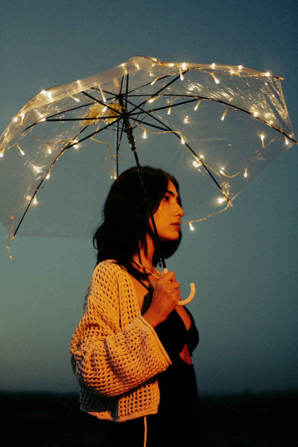 a woman standing under an umbrella with lights on it