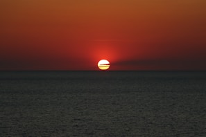 A vibrant sunset over the Red Sea coastline near Jizan, capturing the warm hues and calm waters.