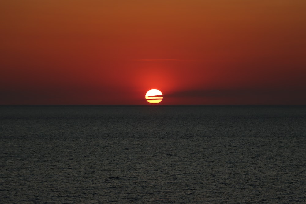 the sun is setting over the ocean on a cloudy day