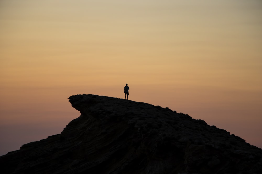 a person standing on top of a mountain at sunset