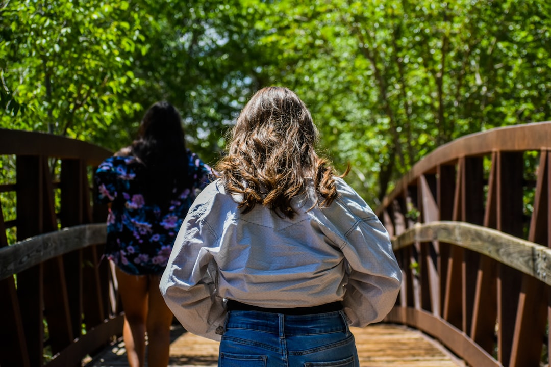 a woman walking across a wooden bridge,