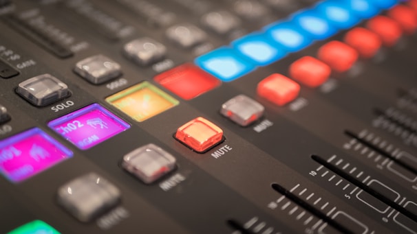 Close-up of audio mixing console with colorful lights and sliders in action.