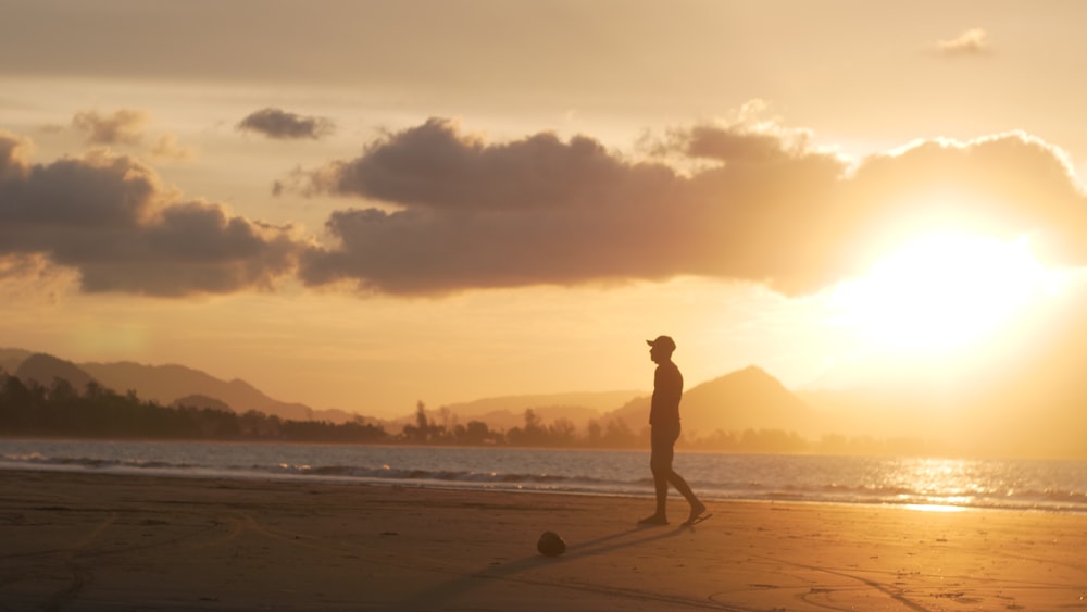 a man standing on top of a beach next to the ocean