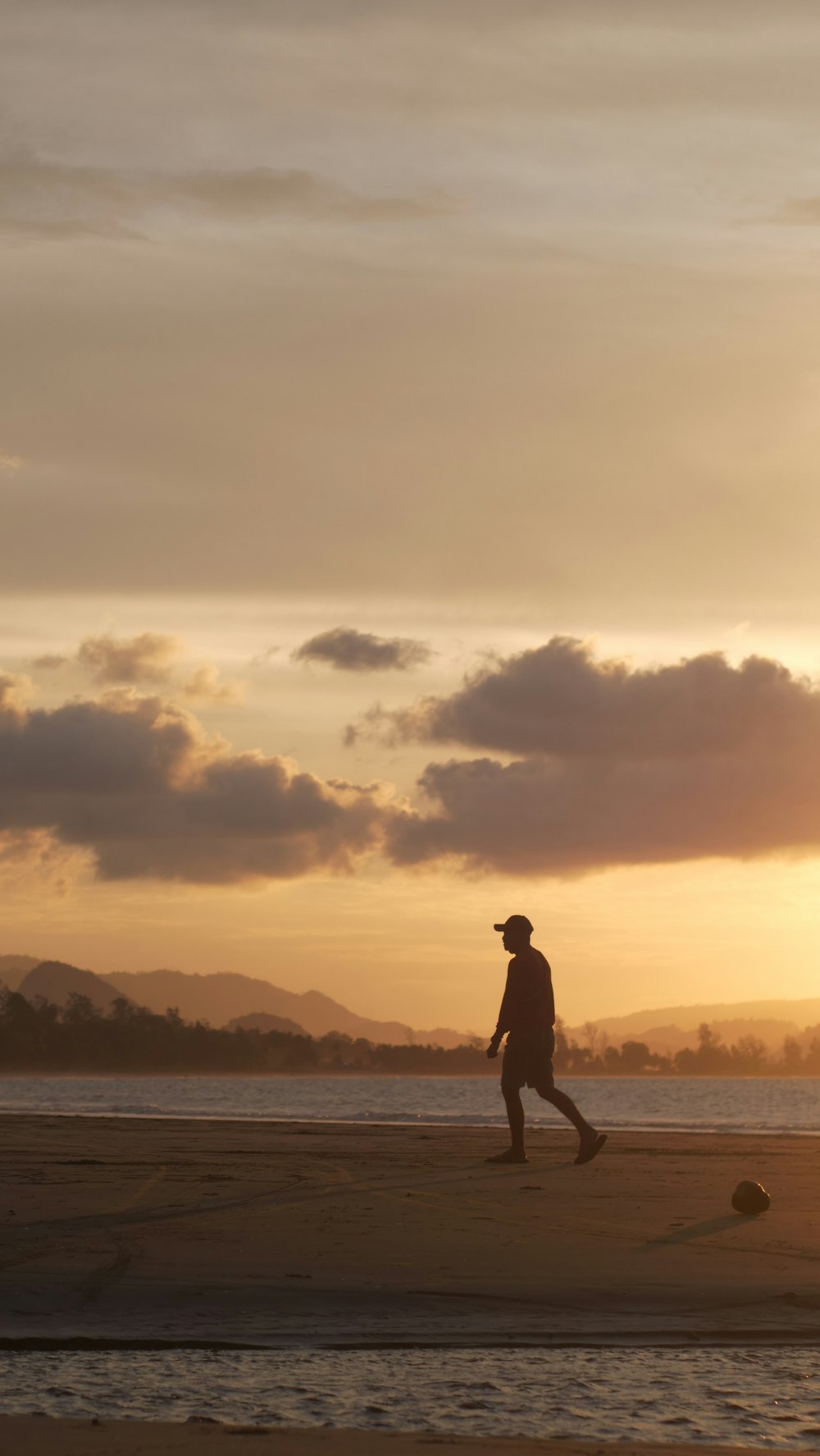 a man walking on the beach at sunset