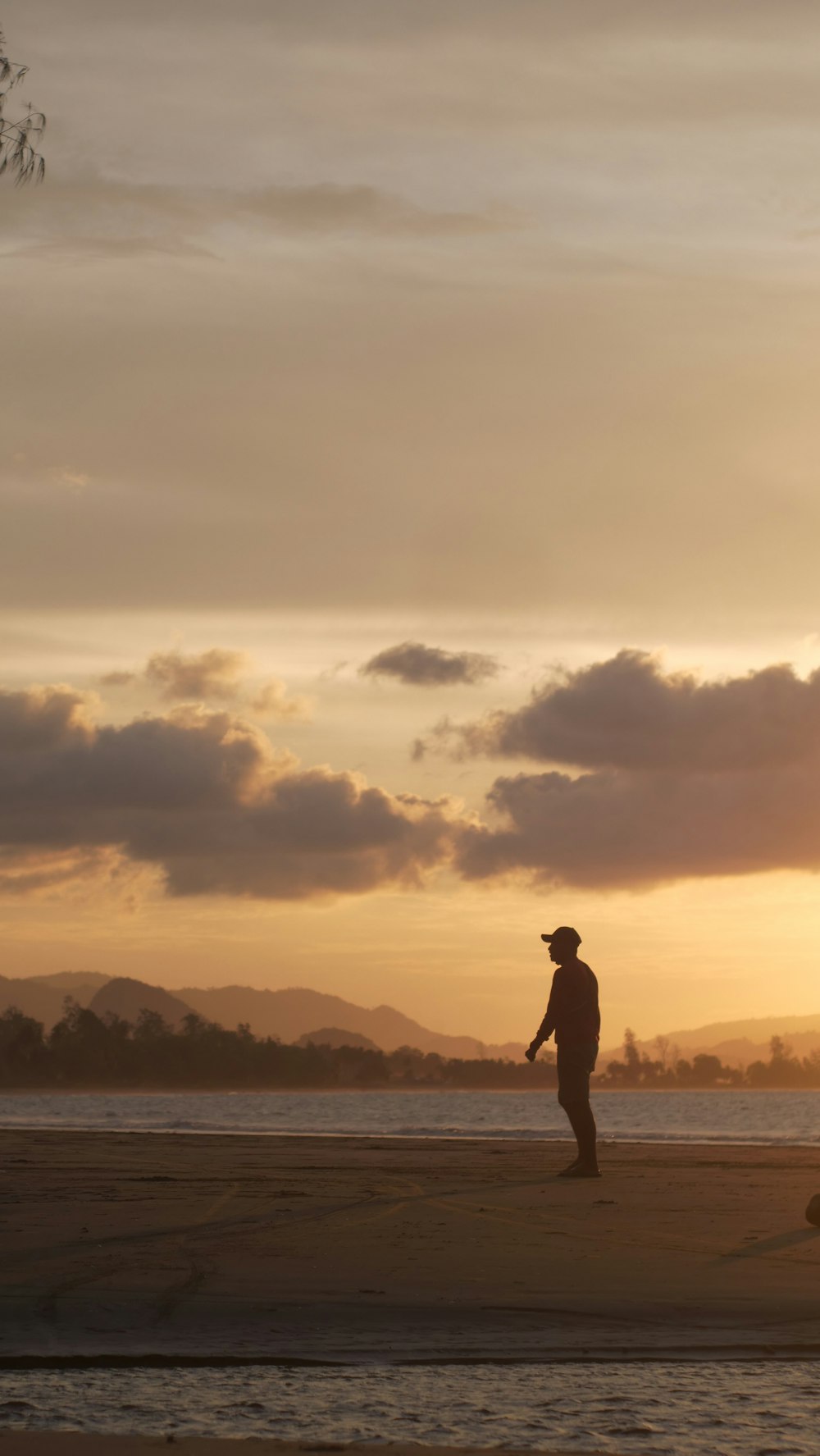 a man standing on a beach at sunset