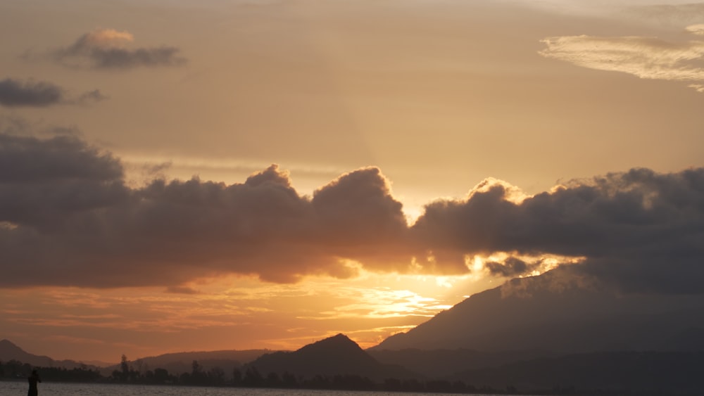 the sun is setting over the mountains and water