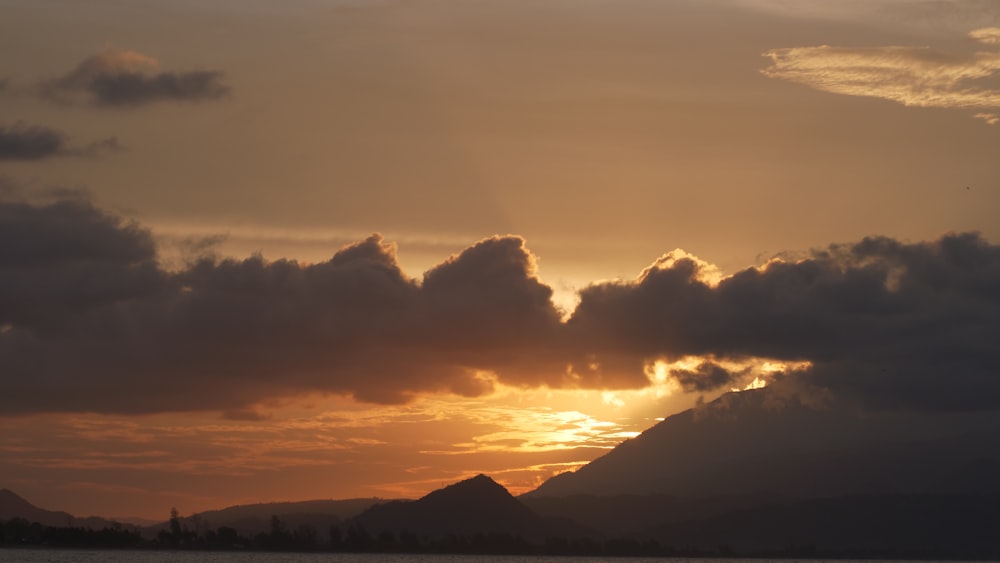 the sun is setting over a mountain range