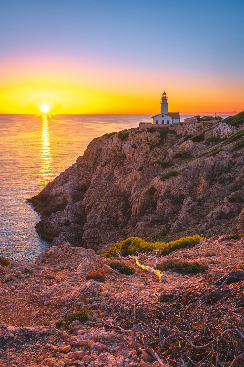 um farol sentado no topo de um penhasco ao lado do oceano