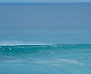 A group of surfers waiting on their boards in calm ocean water before a big wave