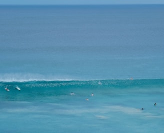 A group of surfers waiting on their boards in calm ocean water before a big wave