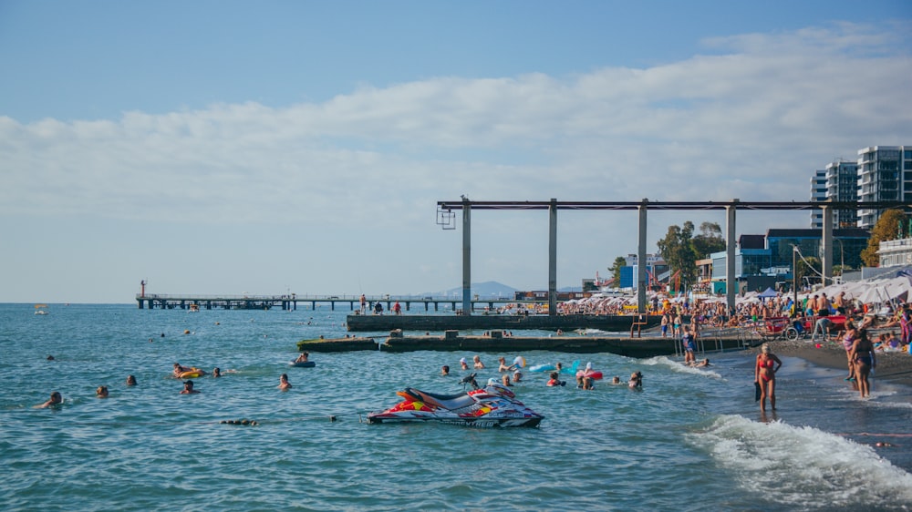 a group of people swimming in the ocean next to a pier