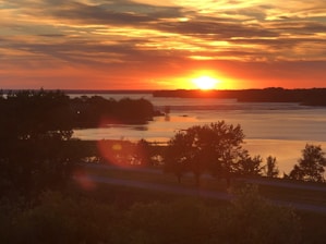 A serene landscape with a sunset casting warm hues over a tranquil lake.