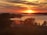 A serene landscape featuring a vibrant sunset over a calm lake.