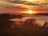 A serene landscape featuring a vibrant sunset over a calm lake.