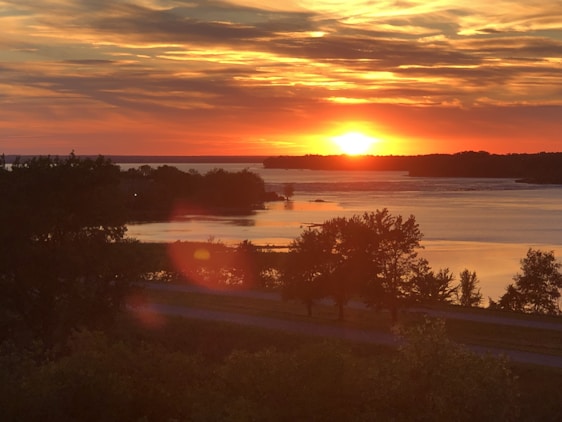 A serene landscape with a vibrant sunset casting warm colors over a tranquil lake.